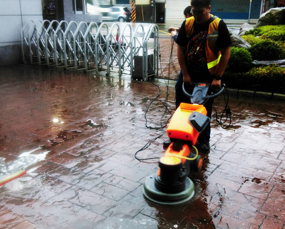 worker-cleaning-brick-floor-outside-with-machine